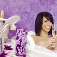 Frau sitzt in Badewanne mit Glas Sekt in der Hand